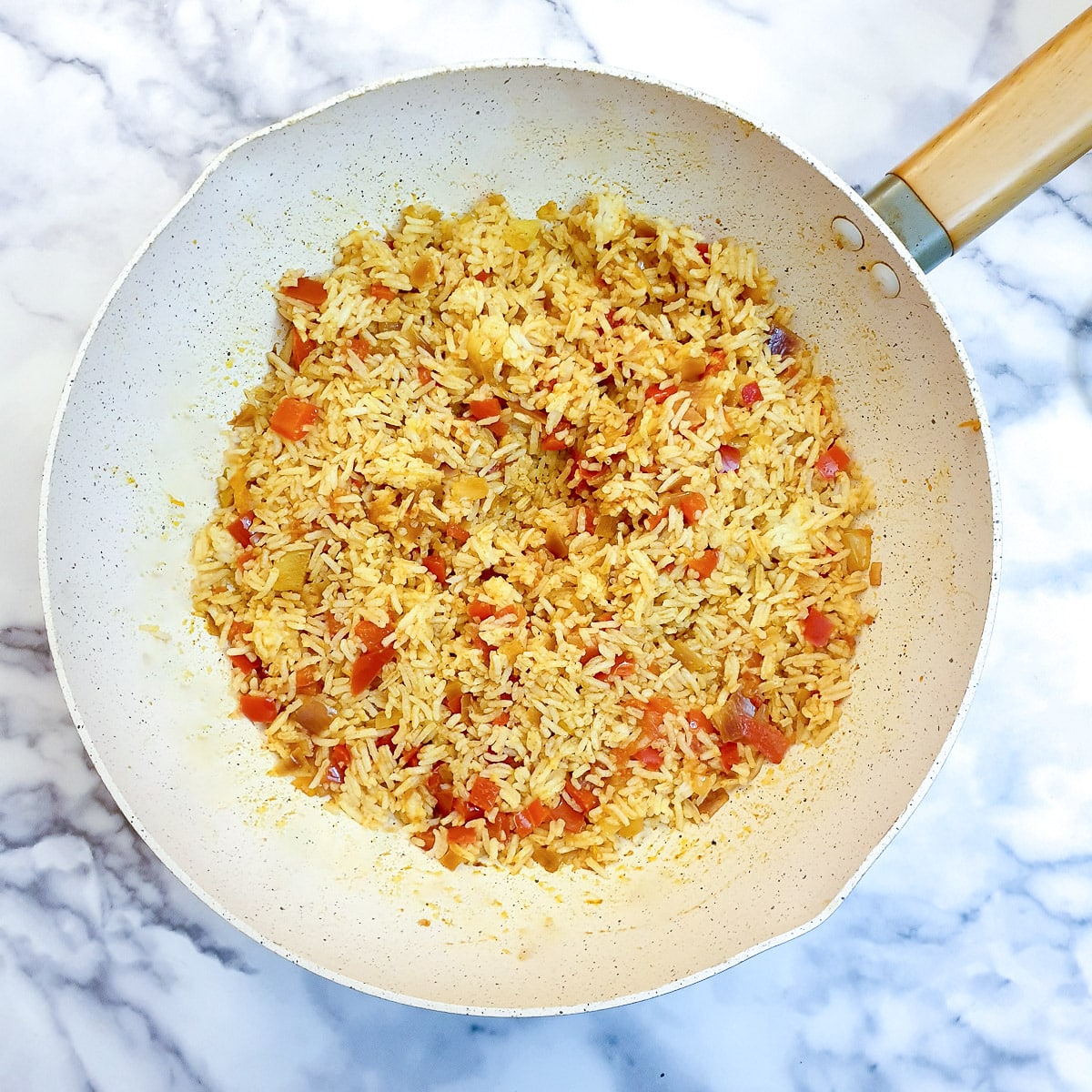 Cooked rice stirred into the Moroccan spices in a wok.