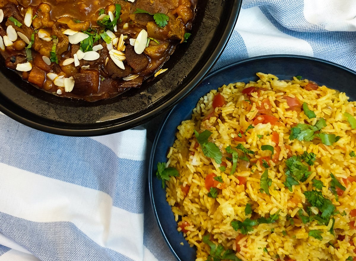 A dish of spicy Moroccan rice next to a bowl of lamb stew.