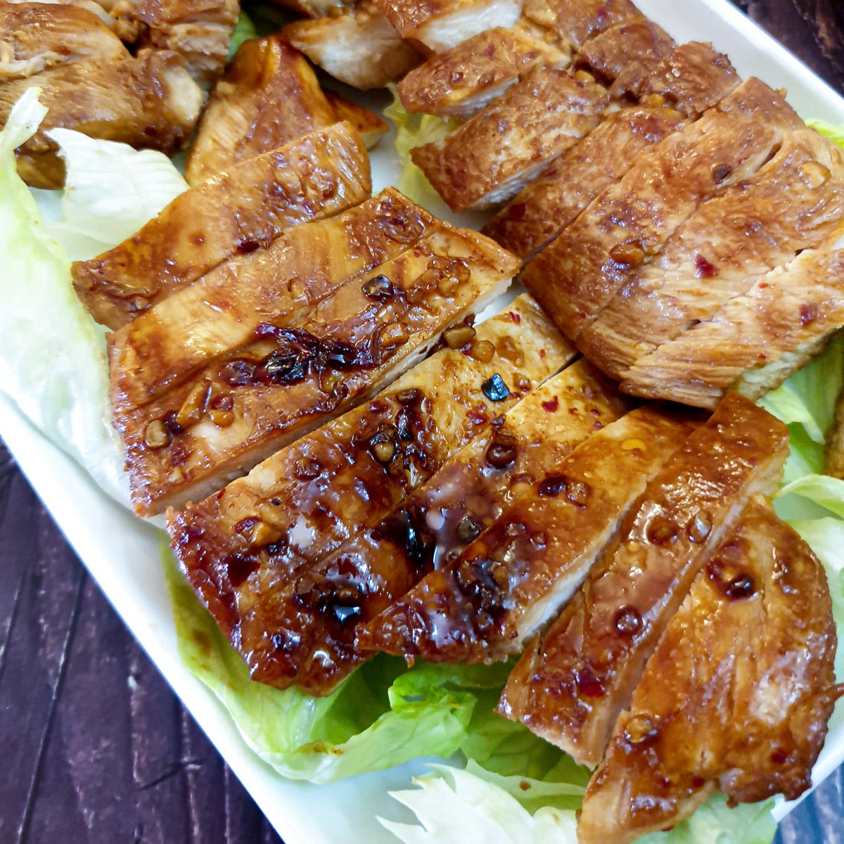 Close up of a plate of sliced honey garlic chicken breasts.