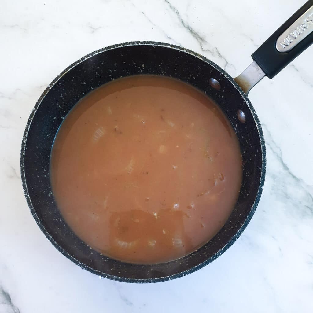 Onion gravy simmering in a pan.