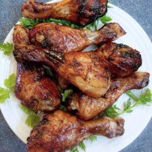 A pile of sweet and spicy chicken drumsticks on a plate.