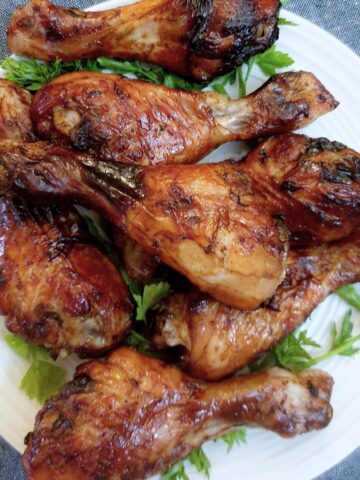 A pile of sweet and spicy chicken drumsticks on a plate.