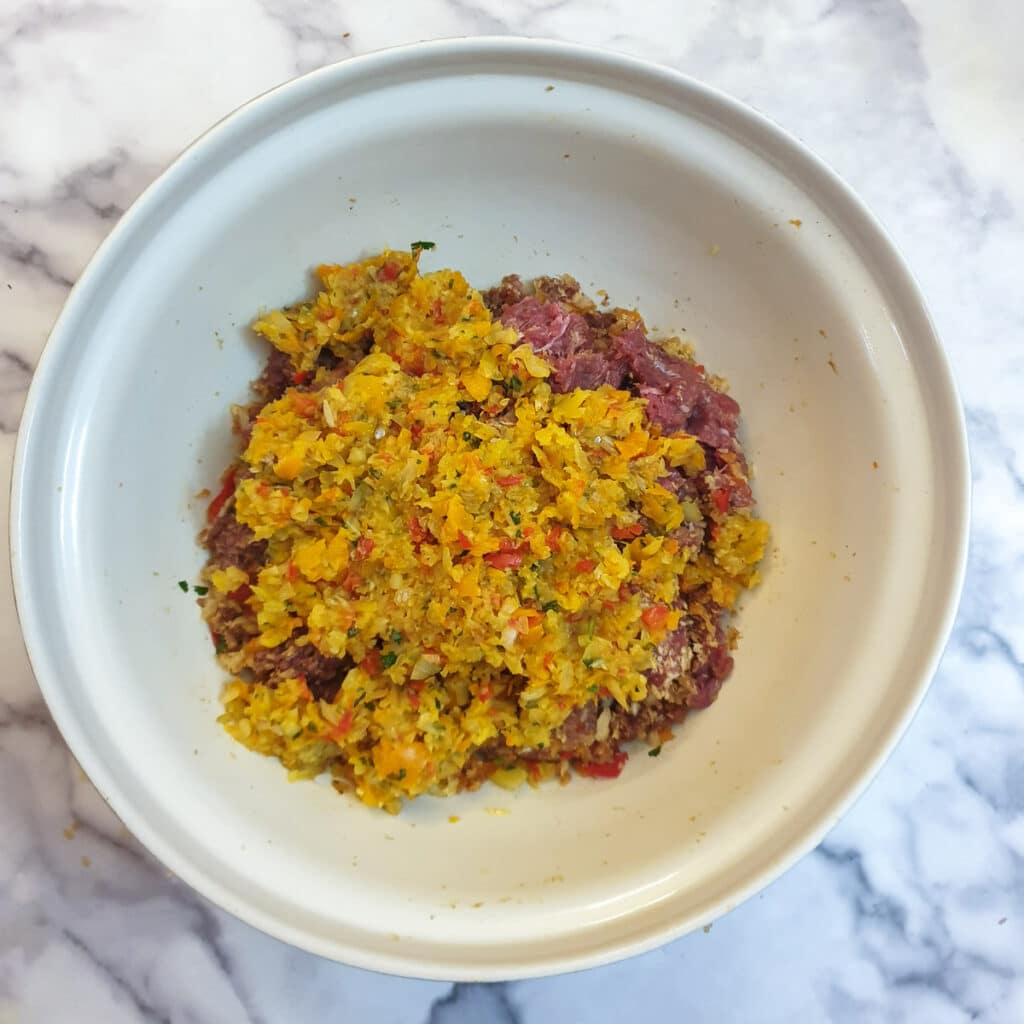 Softened onions and red peppers added to the kofta ingredients in a mixing bowl.