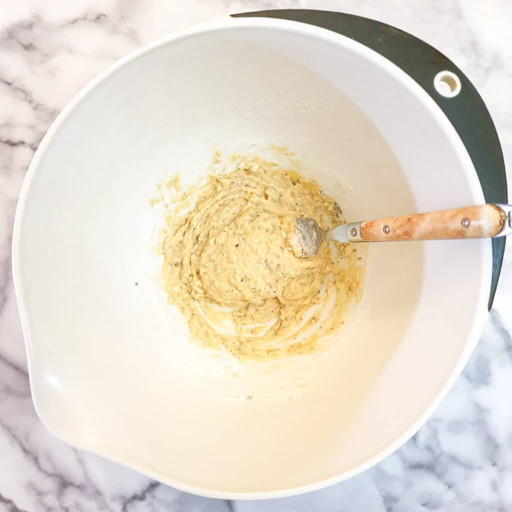 Eggs, flour and mixed herbs mixed to a batter in a mixing bowl.