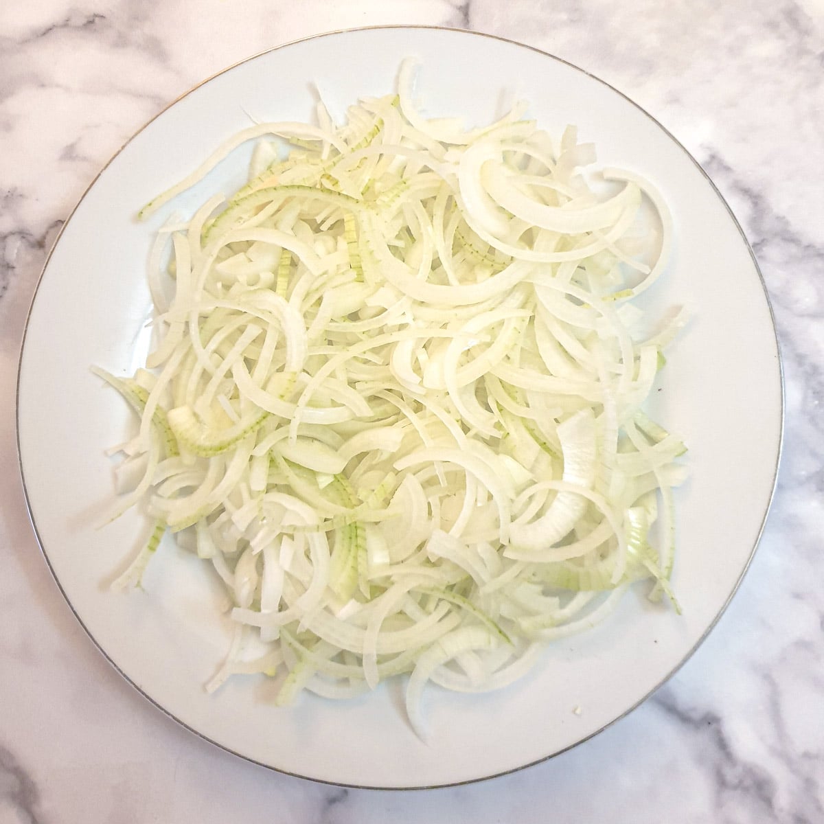 A pile of sliced onions on a white plate.