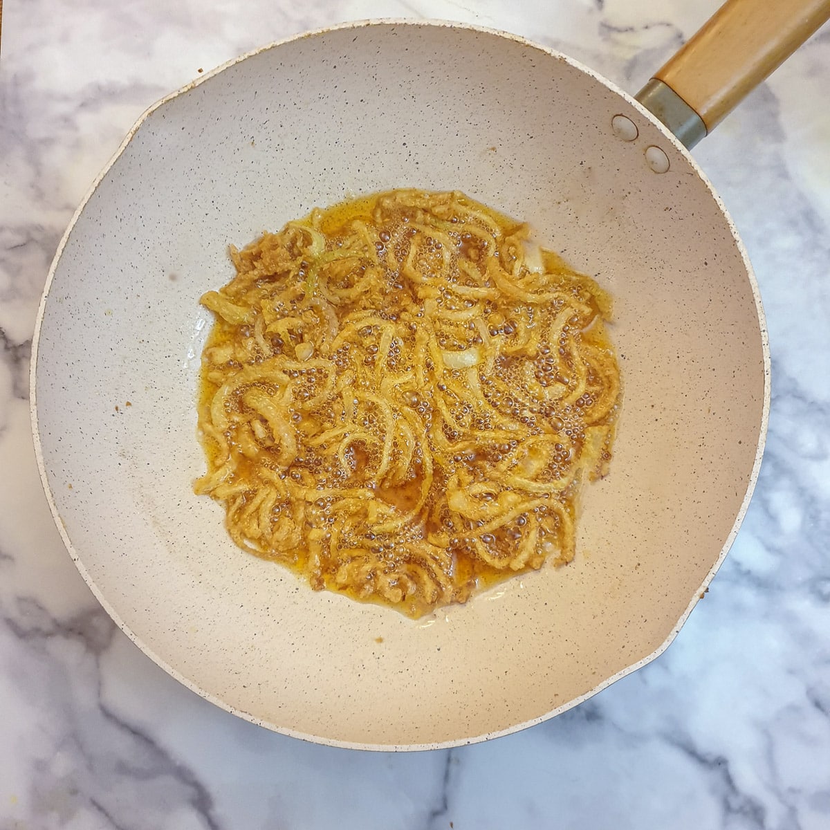 Sliced onions frying in a wok.