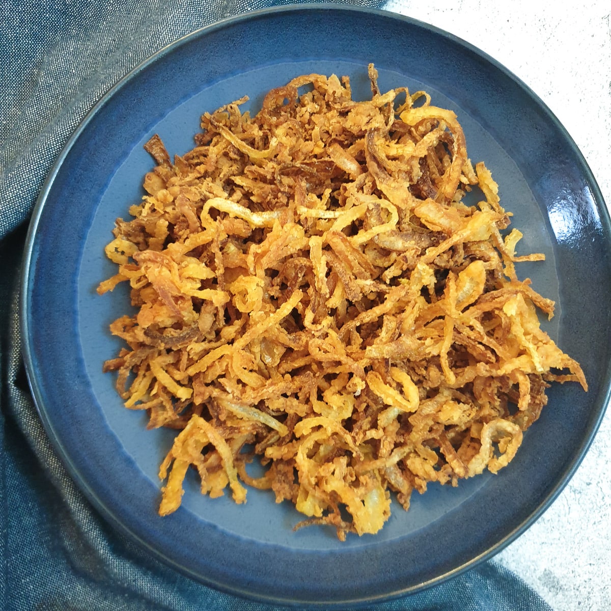 Crispy fried onions in a blue dish.