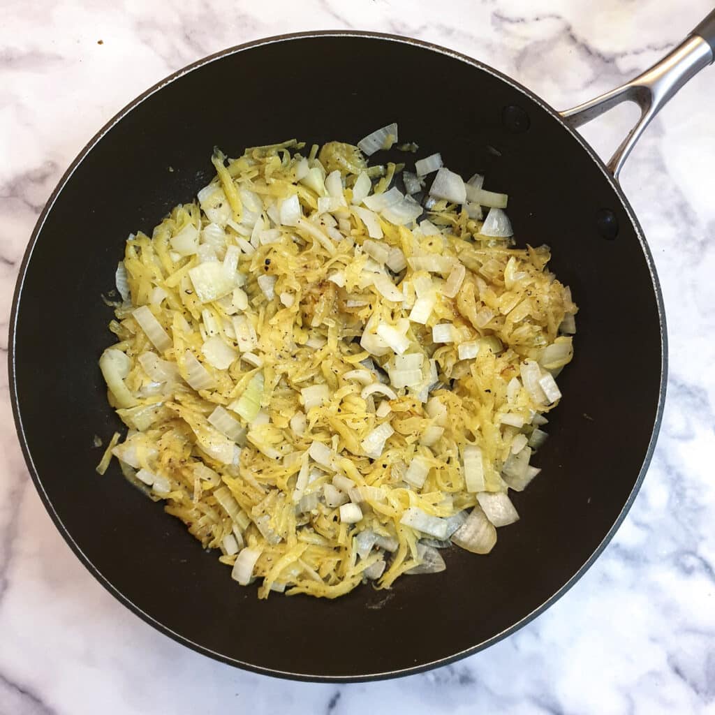 Onions and grated potatoes in a frying pan.