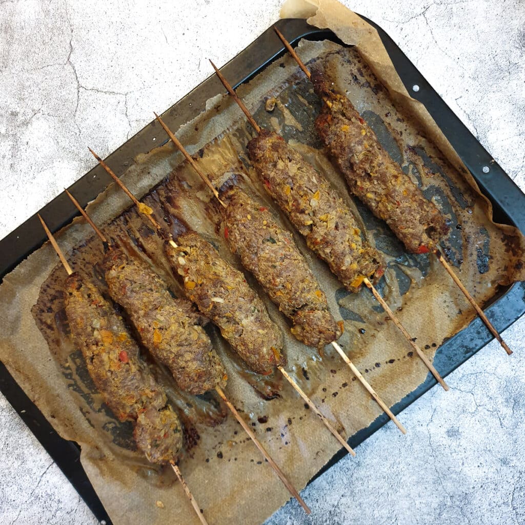 6 baked lamb kofta on a baking sheet.