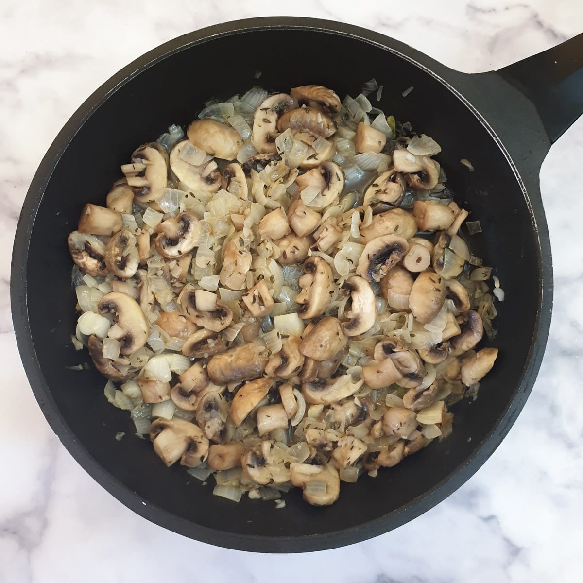 Flour stirred into mushrooms and onions in a frying pan.