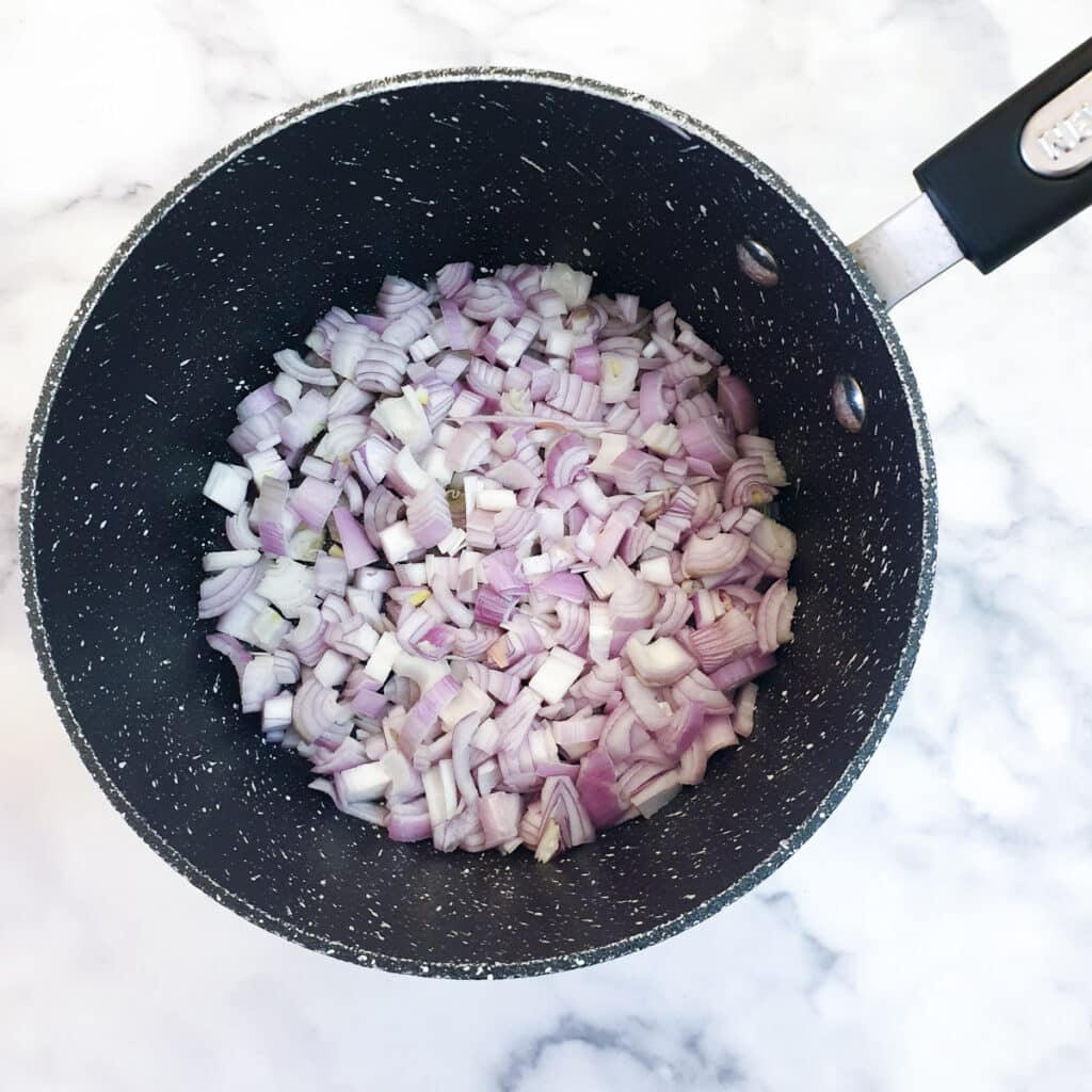 Chopped shallots in a saucepan.