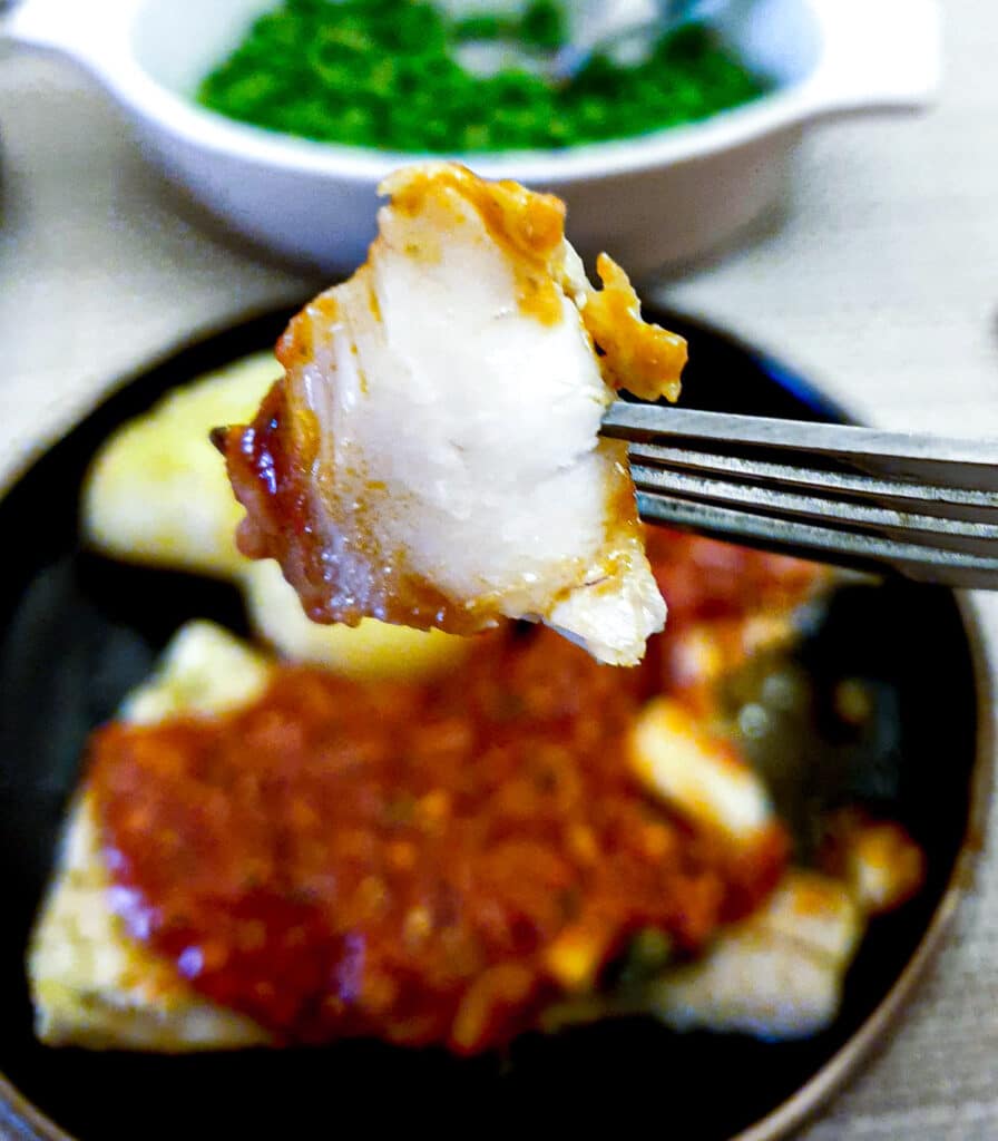 Close up of a piece of mediterranean cod on a fork, showing the flaky texture.