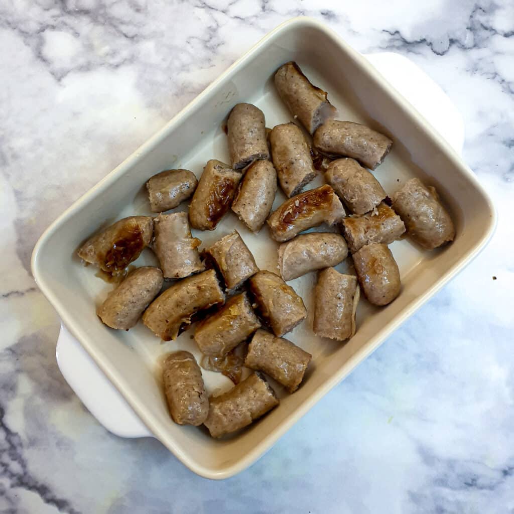 Pieces of sausages arranged in a casserole dish.