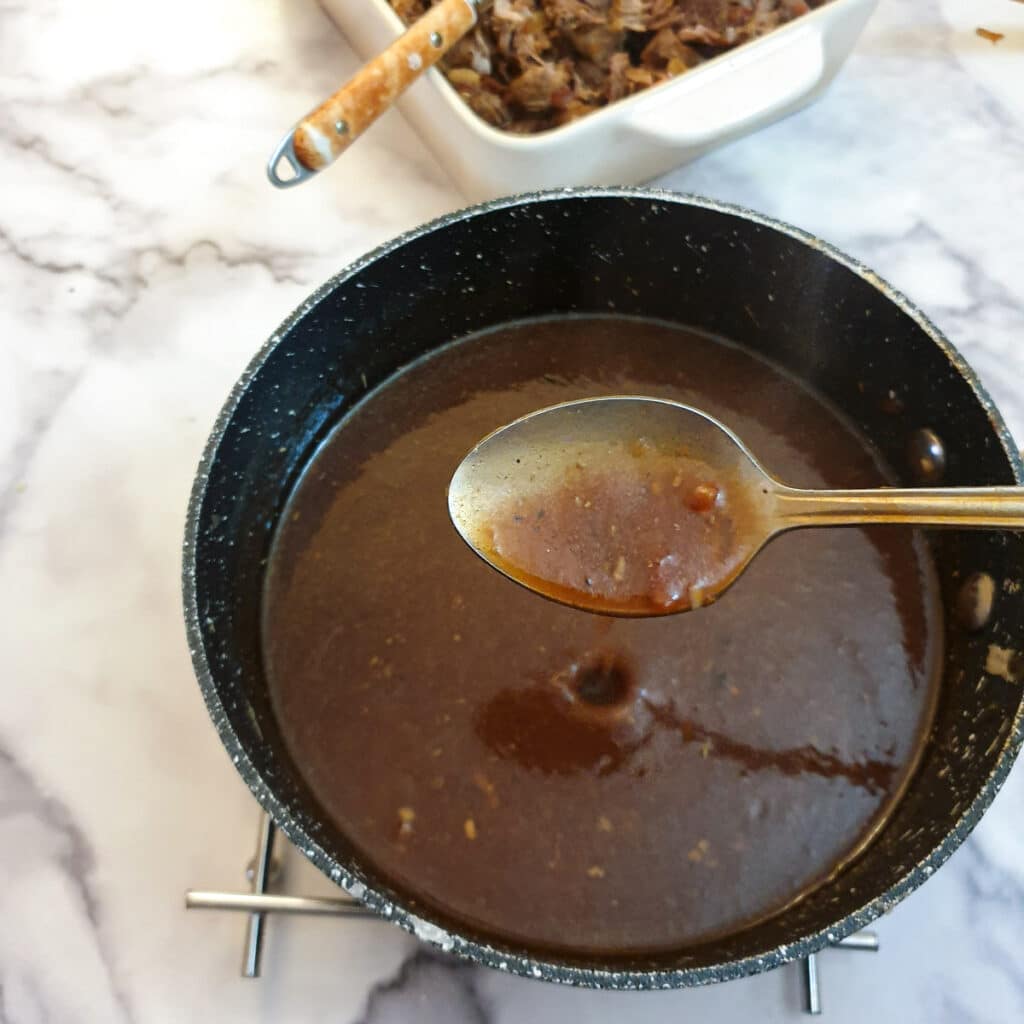 Thickened gravy in a saucepan with a spoon showing the consistency.