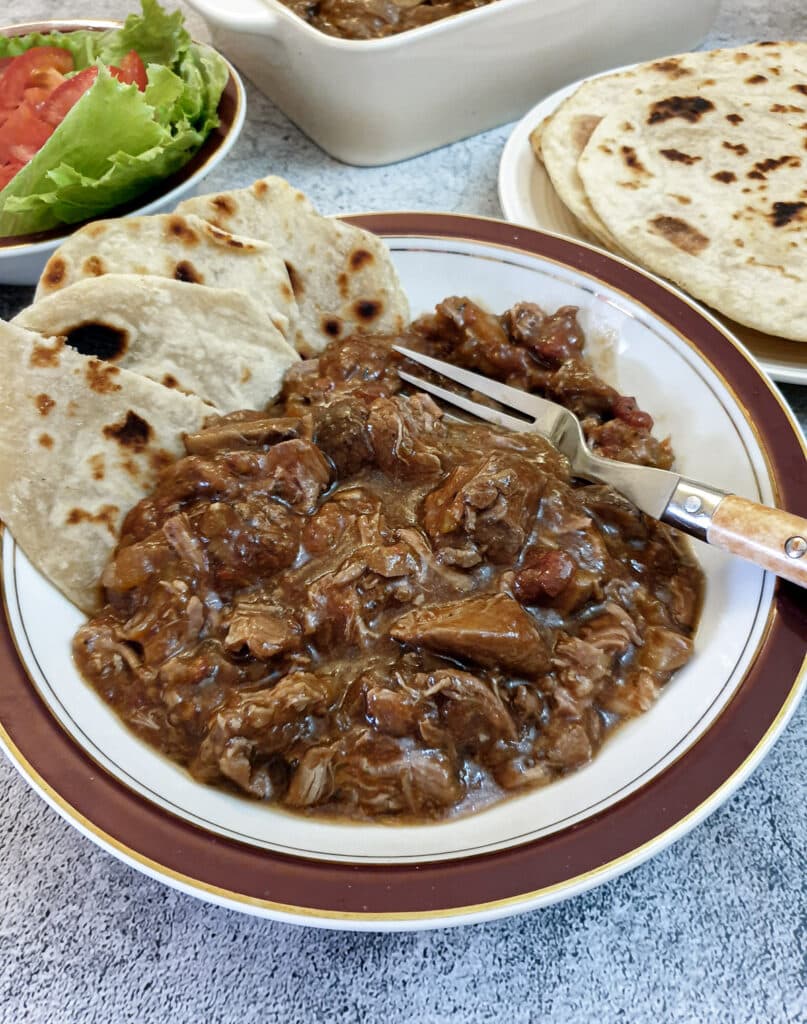 A bowl of lamb ragu with slices of flat bread.