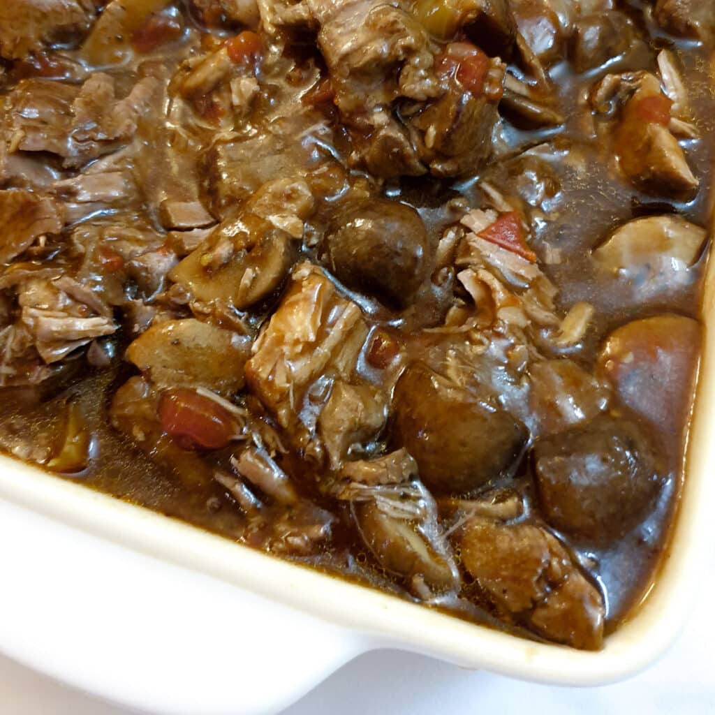 Close up of lamb ragu in a white dish.