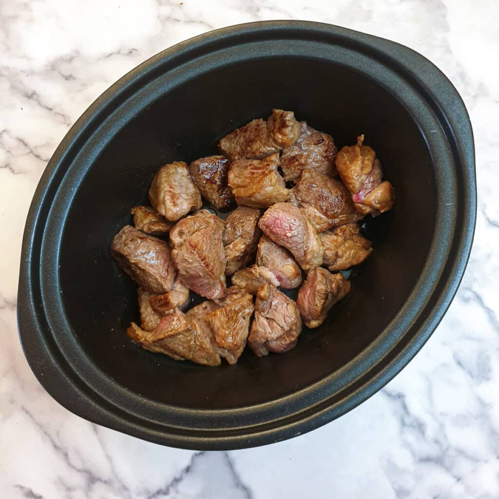 Pieces of lamb in a slow cooker.