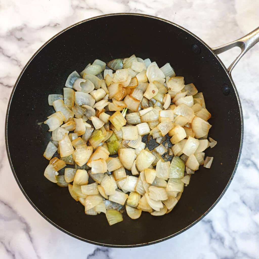 Onions being browned in a frying pan.