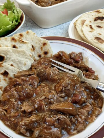 A bowl of lamb ragu with slices of flat bread.