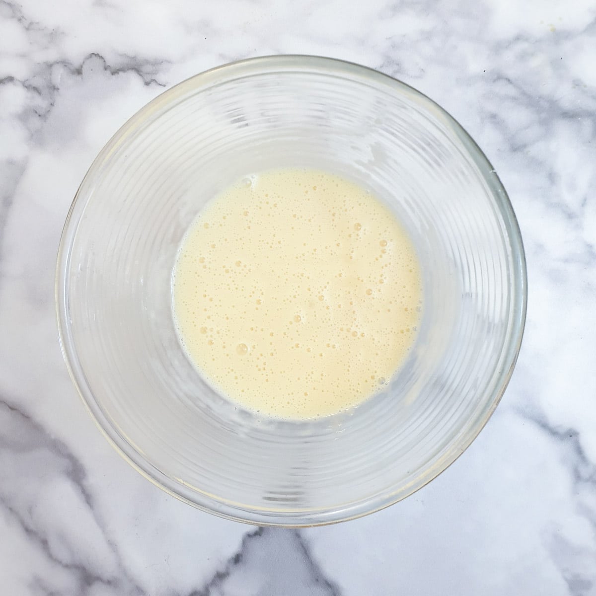 Eggs and cornflour mixed in a glass bowl.
