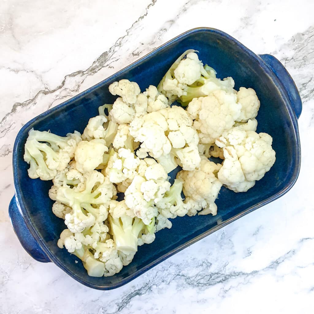 Steamed cauliflower florets in a blue baking dish.