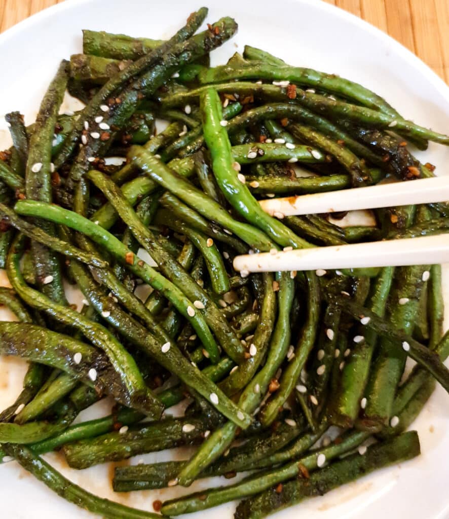 Chinese garlic green beans being picked up with chopsticks.