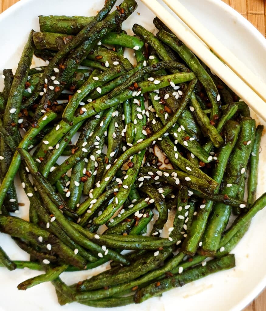 A plate of Chinese garlic green beans garnished with sesame seeds.
