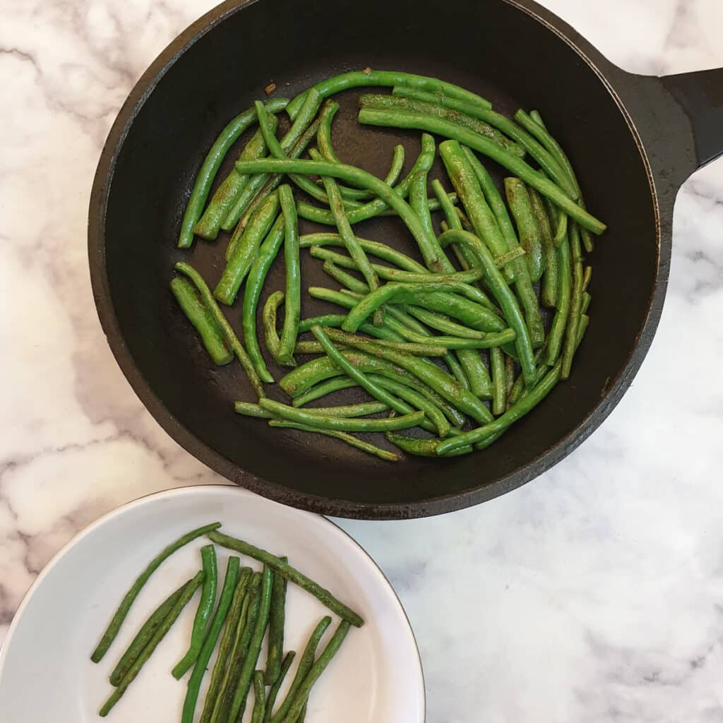 Green beans charring in a frying pan.