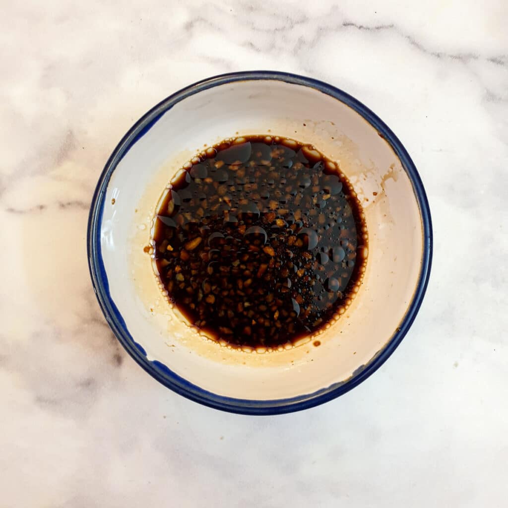 A small white bowl containing the sauce for the beans.