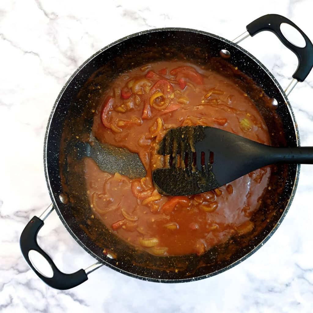 A pan of curried onion sauce with a spatula, showing the consistency of the sauce.