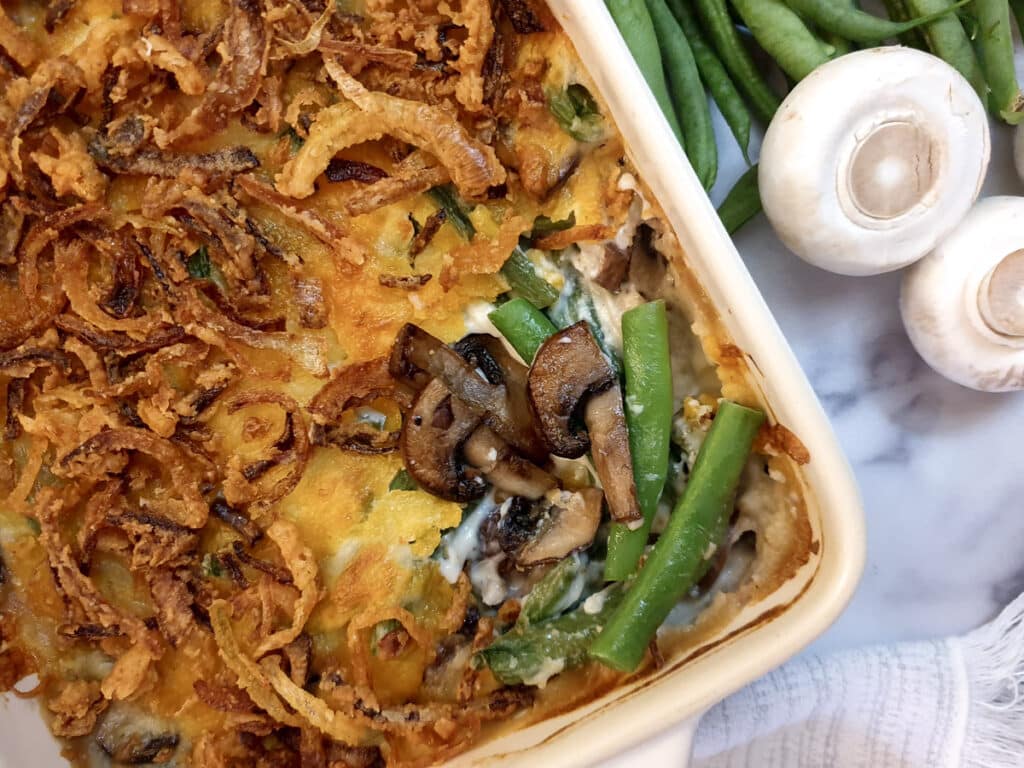 Overhead shot of a green bean casserole showing the crispy onion topping and the beans and mushrooms in the filling.