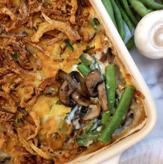 Overhead shot of a green bean casserole showing the crispy onion topping and the beans and mushrooms in the filling.