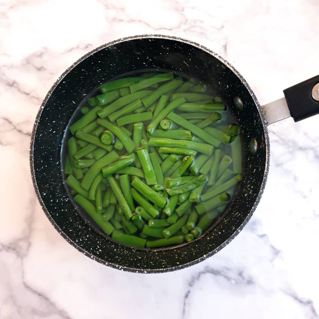 A saucepan of green beans in water.