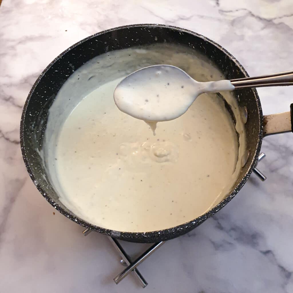 White sauce in a saucepan showing the consistency.