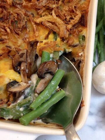 Overhead shot of a green bean casserole topped with crispy onions, being served with a spoon.