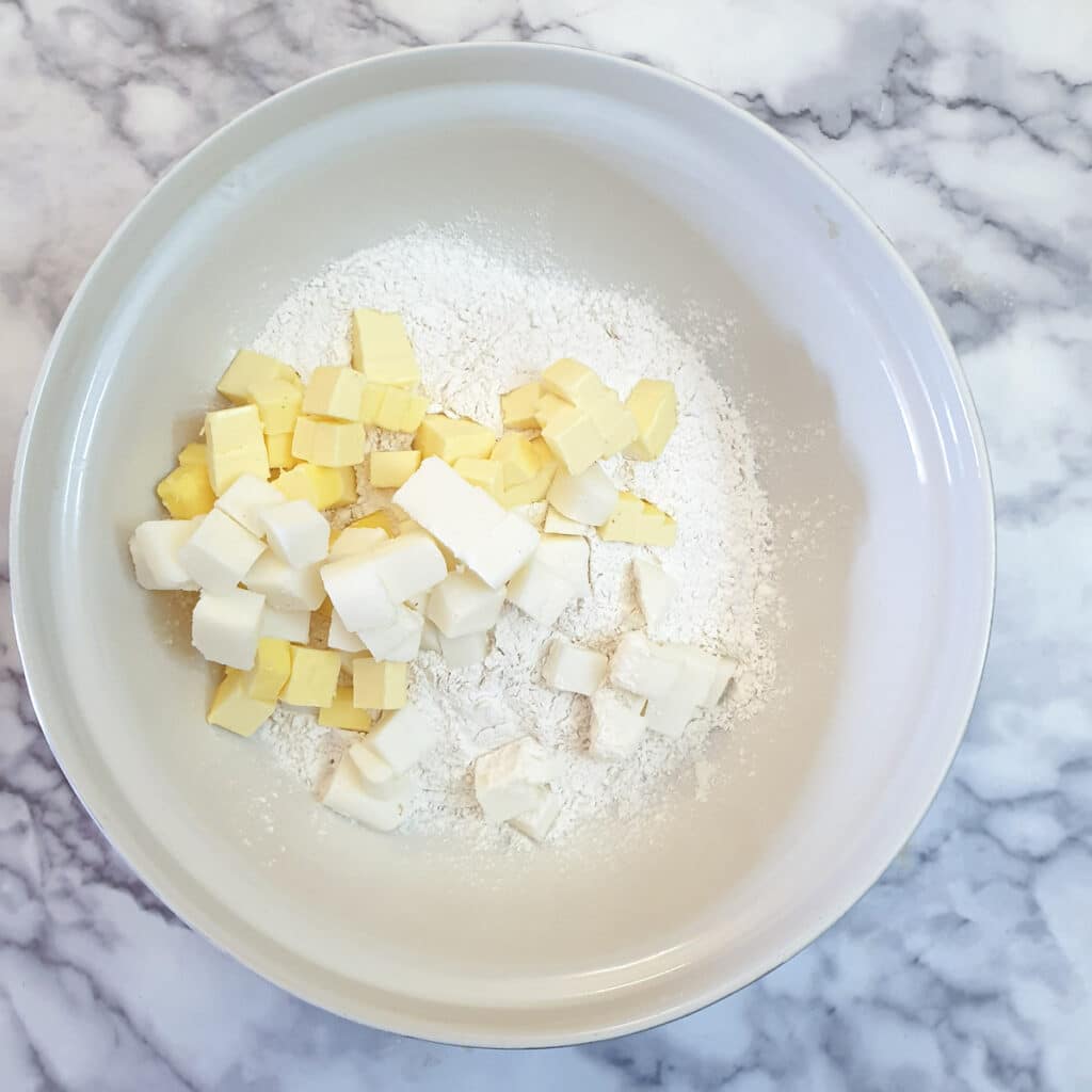 Cubed butter and lard in a mixing bowl with flour.