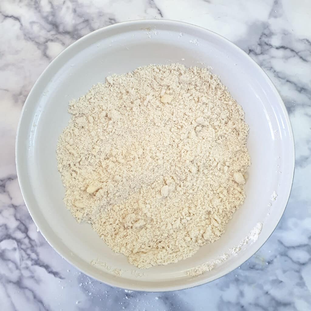 Butter and lard rubbed into a bowl of flour to form a breadcrumb-like mixture.