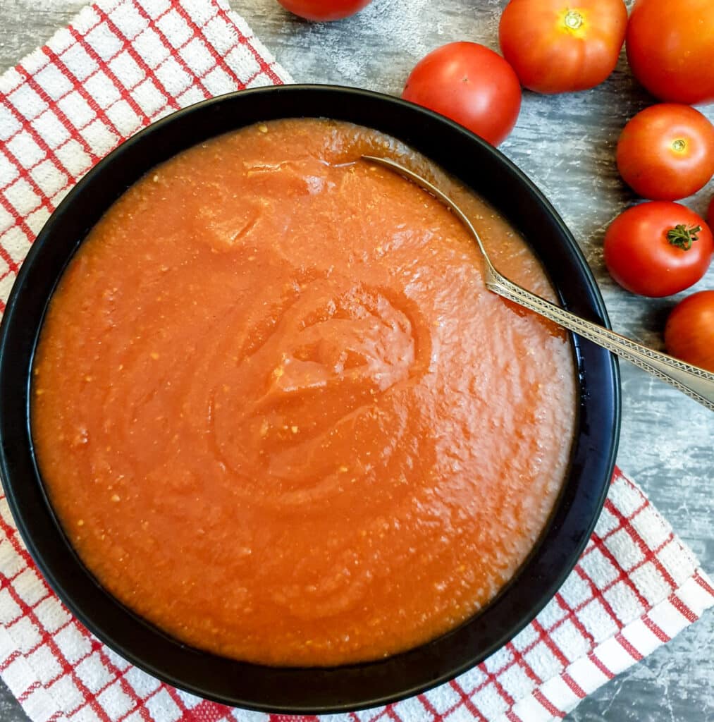 Passata in a black dish with a spoon.