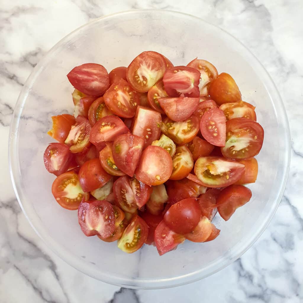 A bowl of tomatoes that have been cut into quarters.