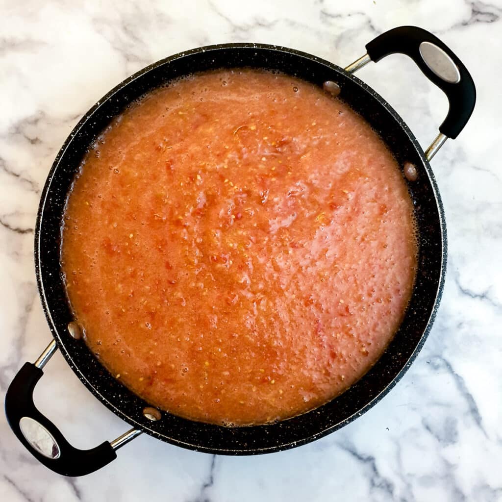 Tomato pulp transfered to a frying pan.