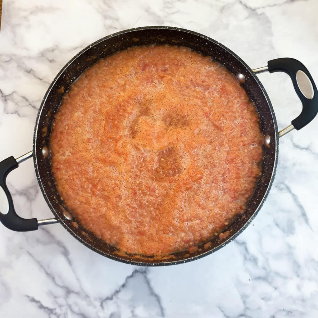 Tomato passata in a frying pan showing the scum that forms on top.