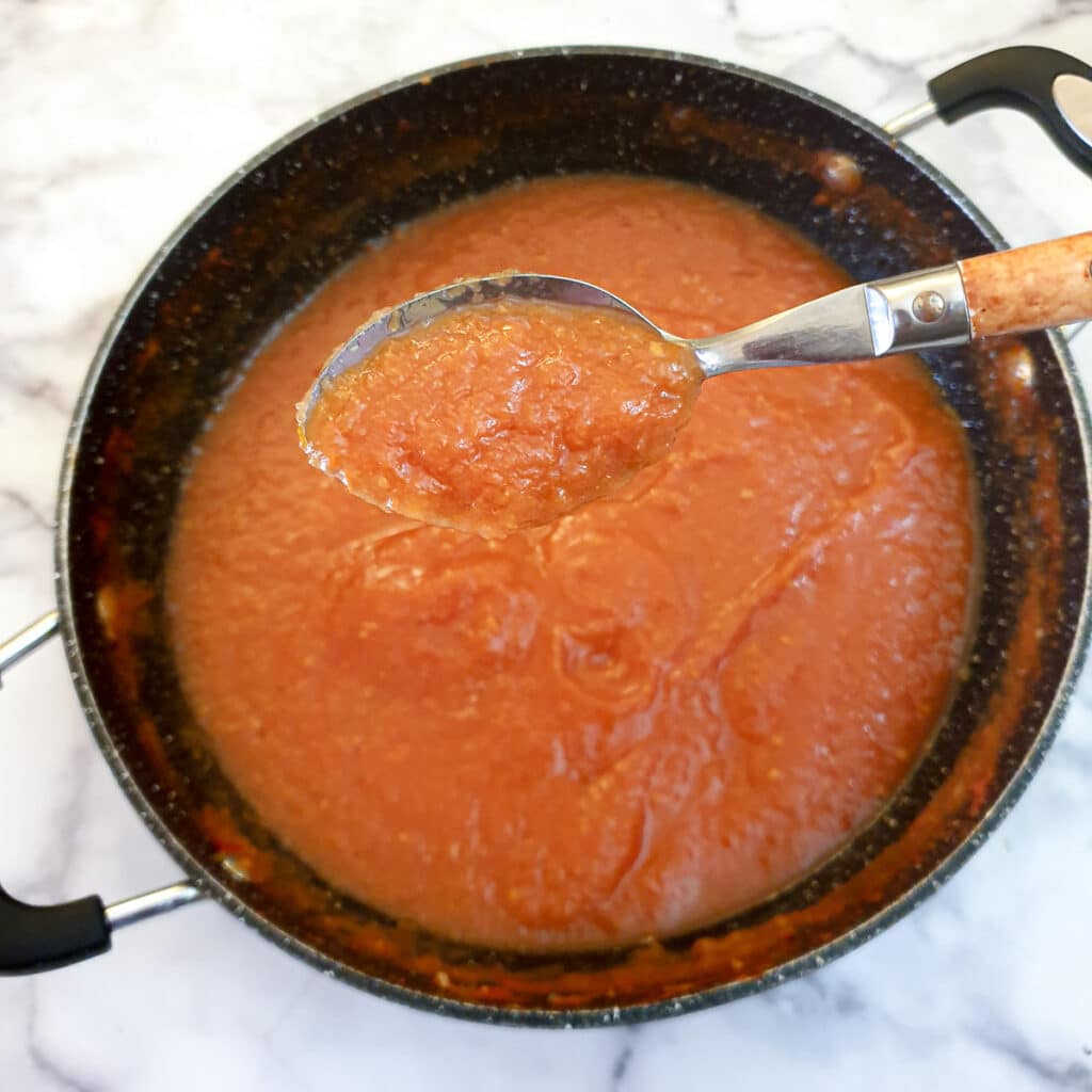 A frying pan containing fully cooked and thickened passata.