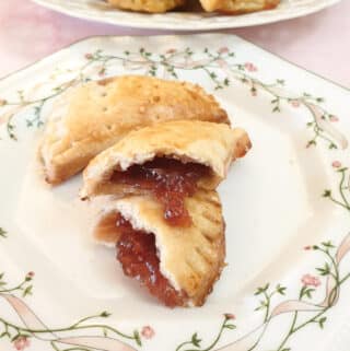 A jam turnover opened to show the jam oozing out, on a cake plate
