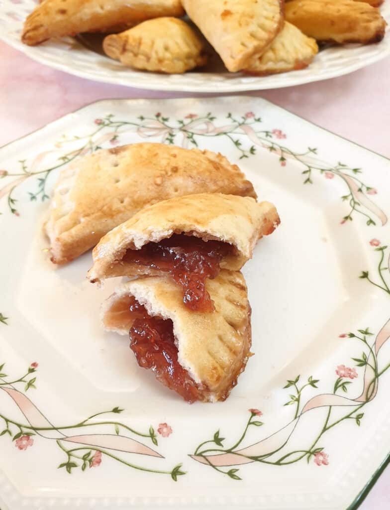 A jam turnover opened to show the jam oozing out, on a cake plate