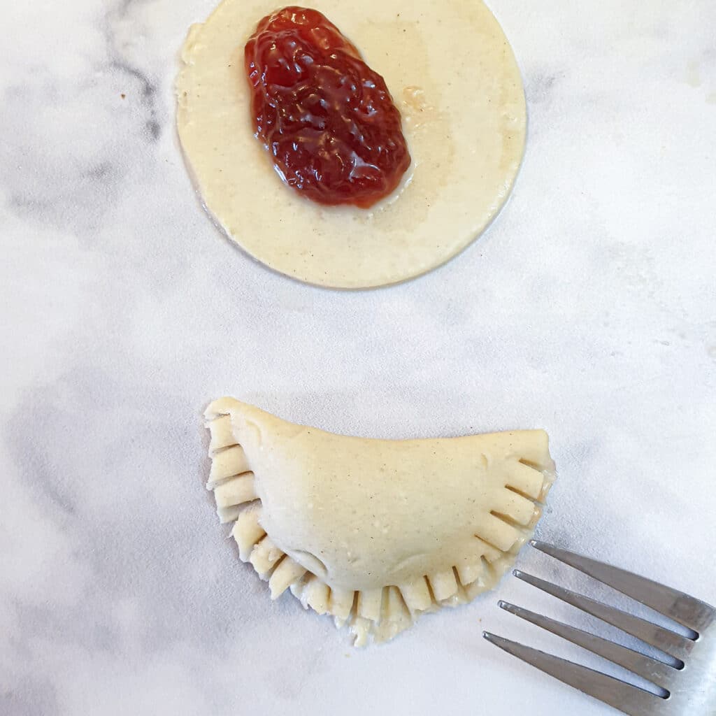 A circle of pastry folded over to form a half moon shape, crimped with a fork to seal the edges.