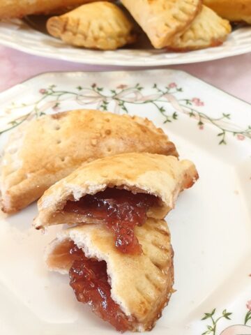 A jam turnover opened to show the jam oozing out, on a cake plate