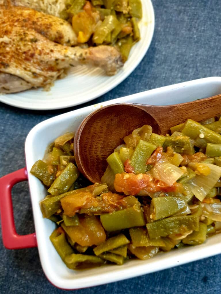 A dish of Middle Eastern-style runner beans with a wooden serving spoon.