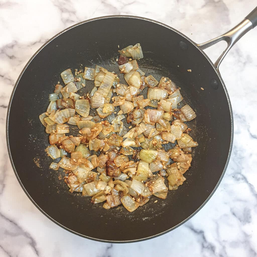 Onions, garlic and spices in a frying pan.