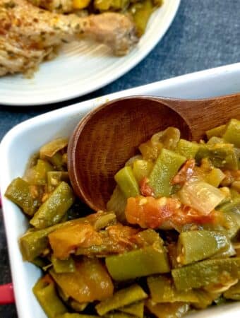 A dish of Middle Eastern-style runner beans with a wooden serving spoon.