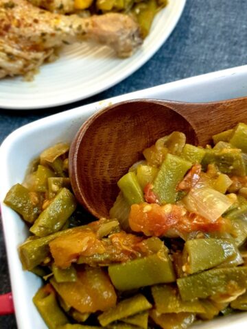 A dish of Middle Eastern-style runner beans with a wooden serving spoon.